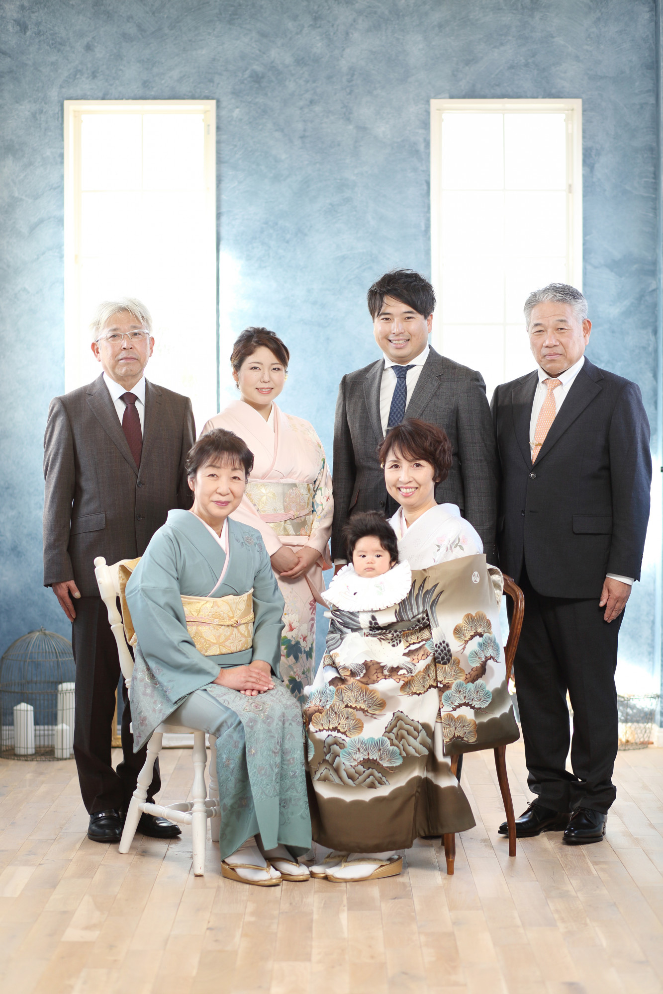 祝着を着た赤ちゃんと着物を着た母親・祖母とスーツを着た家族の記念写真